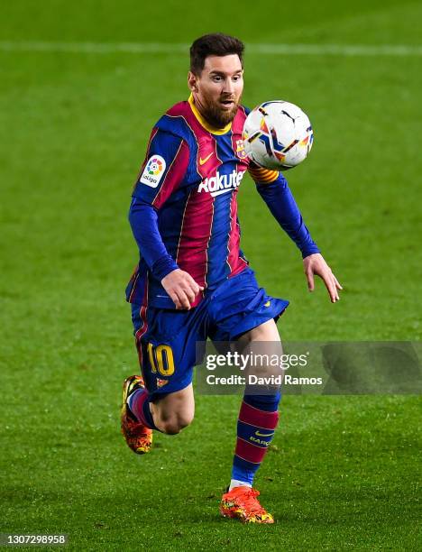 Lionel Messi of FC Barcelona runs with the ball during the La Liga Santander match between FC Barcelona and SD Huesca at Camp Nou on March 15, 2021...