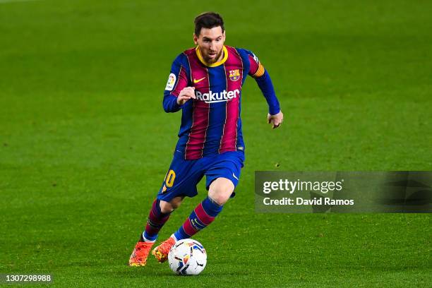 Lionel Messi of FC Barcelona runs with the ball during the La Liga Santander match between FC Barcelona and SD Huesca at Camp Nou on March 15, 2021...