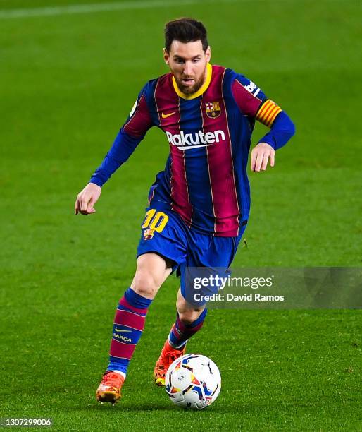 Lionel Messi of FC Barcelona runs with the ball during the La Liga Santander match between FC Barcelona and SD Huesca at Camp Nou on March 15, 2021...