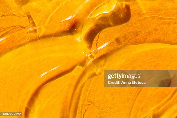 cosmetic background consisting of smears of cosmetic gel on bright orange background. concept of trendy body care procedures of the year - orange creme stock pictures, royalty-free photos & images