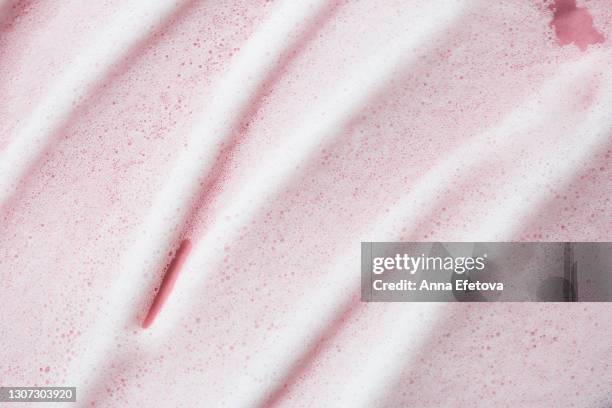 texture of white foam on rose background. selfcare is a trendy procedure of the year. cosmetics banner with copy space - bubbelbad stockfoto's en -beelden