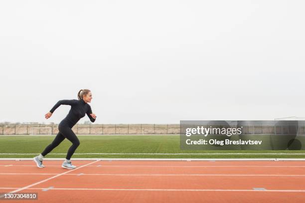 female athlete doing powerful interval running training and speed up on stadium running track - sportlichkeit stock-fotos und bilder