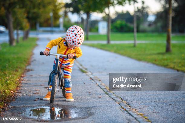 caucasian boy driving balance bike outdoors - puddle stock pictures, royalty-free photos & images