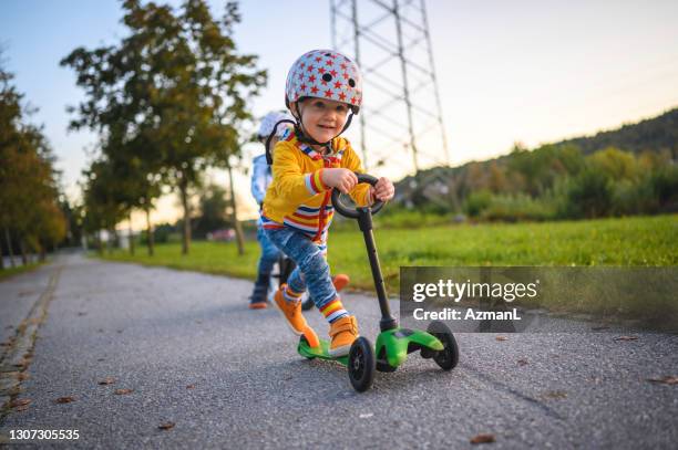 caucasian brothers driving balance bike and push scooter outdoors - trotinete imagens e fotografias de stock