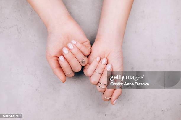 woman hands with nude pink manicure and with many various silver rings on fingers on concrete gray background. concept of trendy boho style. flat lay style with copy space - リング ストックフォトと画像