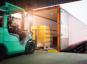 Forklift Driver Loading Package Boxes into Cargo Container. Cargo Trailer Truck Parked Loading at Dock Warehouse. Shipment Delivery Service. Shipping Warehouse Logistics. Freight Truck Transportation.