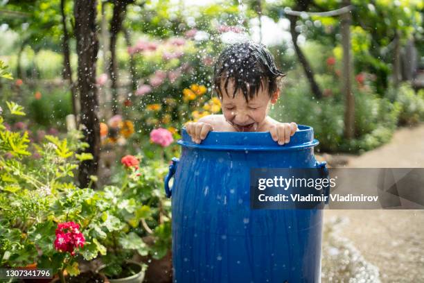 small boy taking bath in a water tank in the garden - rainwater tank stock pictures, royalty-free photos & images