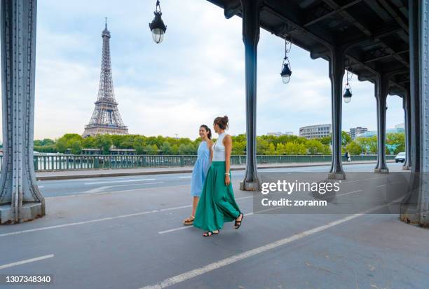 zwei junge frauen schlendern auf der brücke über den radweg - paris summer stock-fotos und bilder