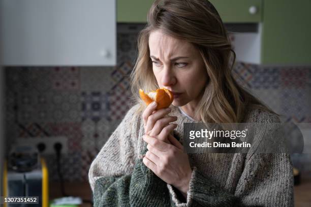 woman trying to sense smell of tangerine orange, has symptoms of covid-19 corona virus infection - symptom stock pictures, royalty-free photos & images
