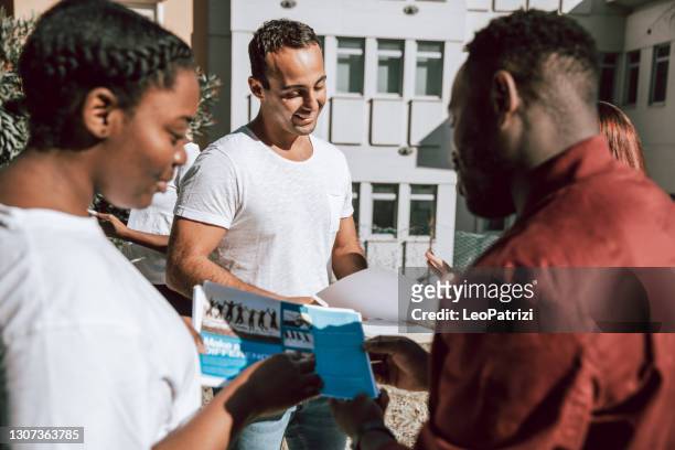 multicultural group of young volunteers distribute flyers and leaflets in the street - flyer leaflet stock pictures, royalty-free photos & images