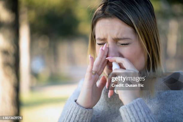 sneezing and taking nasal spray in nature - hayfever stock pictures, royalty-free photos & images