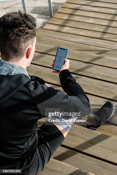man with leg prosthesis using smartphone on stairs - person surfing the internet stock pictures, royalty-free photos & images