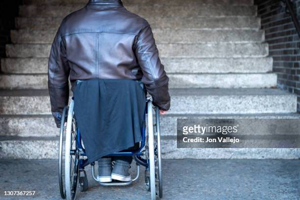 details of a handicapped man sitting in his wheelchair in front of stairs he cannot climb. - social exclusion stock pictures, royalty-free photos & images