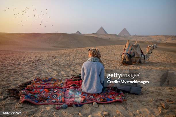 donna guarda il tramonto alle piramidi di giza, guarda attraverso il deserto del sahara - piramide foto e immagini stock