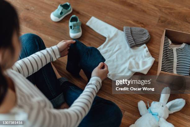 pregnant woman unpacking parcel of baby goods ordered online - babybekleidung stock-fotos und bilder