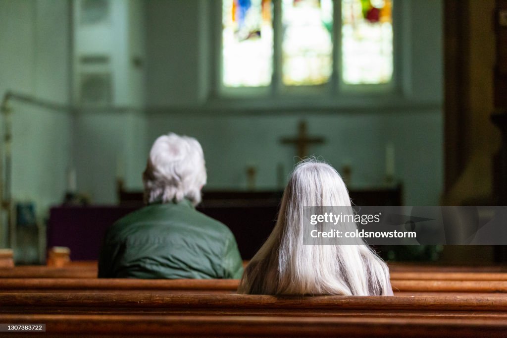 Vue arrière de deux personnes priant dans l’église