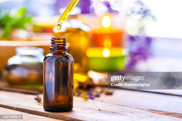 aromarherapy: essential oil bottle on wooden table - homeopathic medicine stock pictures, royalty-free photos & images