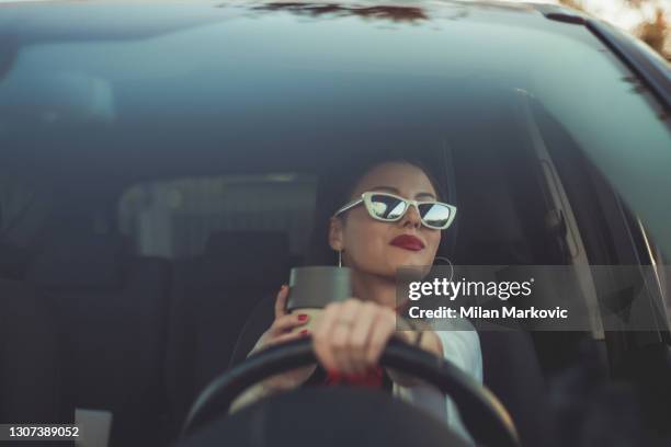 a young and cheerful woman enjoys a new car, sitting inside the car. making a coffee break - coffee car design stock pictures, royalty-free photos & images