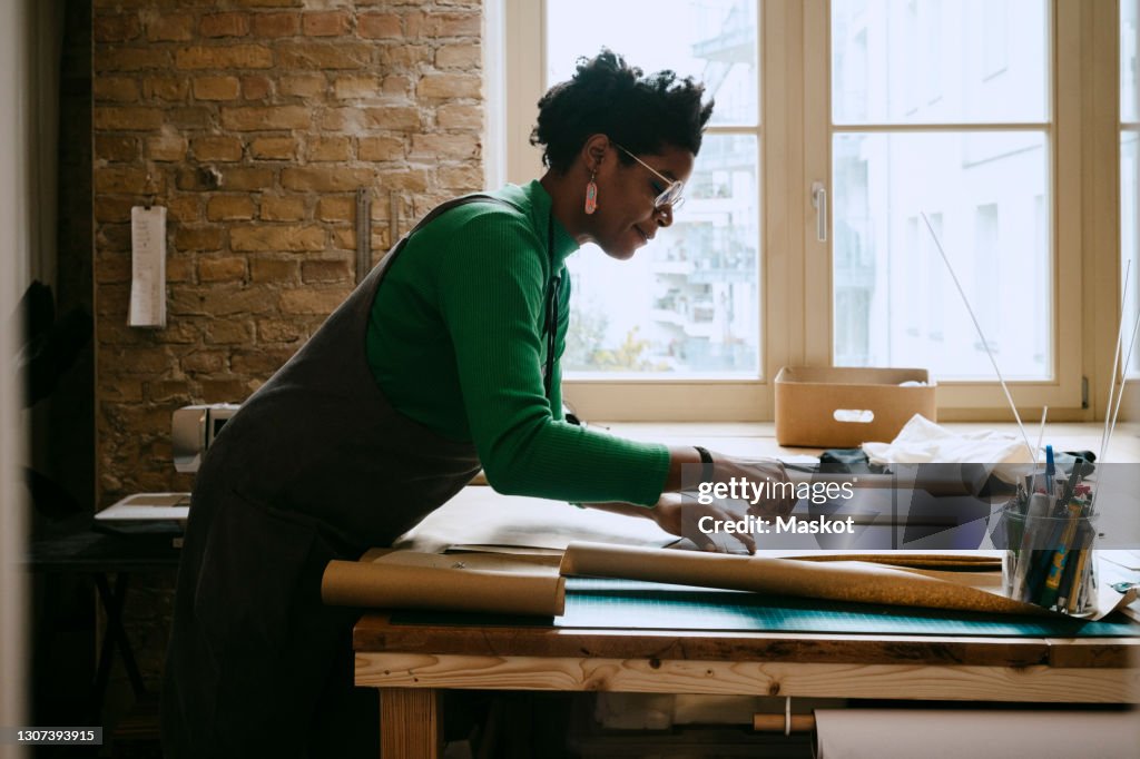 Female artist concentrating while doing craft at table in living room