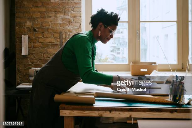 female artist concentrating while doing craft at table in living room - design professional stockfoto's en -beelden