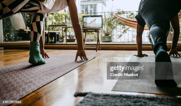 low section of male and female friends e-learning yoga through laptop at home - youtube stock pictures, royalty-free photos & images