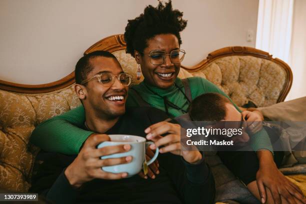 happy female and male friends spending leisure time in living room at home - coffee at home stock-fotos und bilder