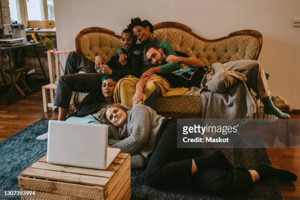 male and female roommates spending leisure time while watching movie through laptop at home - room mates male stock-fotos und bilder