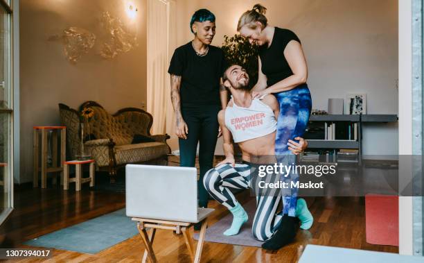 happy male and female friends talking while practicing online yoga at home - room mates male stock-fotos und bilder