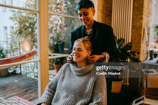 smiling woman pulling female friends ear at home - ear pulling stock pictures, royalty-free photos & images