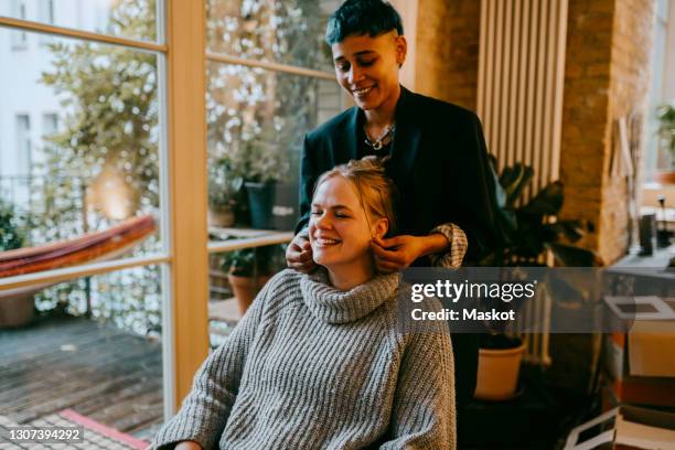 smiling woman pulling female friends ear at home - pulling ear stock pictures, royalty-free photos & images