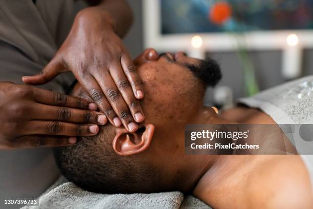 masseuse giving head massage to man in spa - head massage stock pictures, royalty-free photos & images