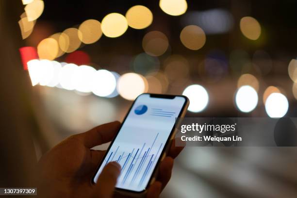 at night, people on the side of the road are watching stock market data - smartphone background stockfoto's en -beelden