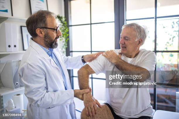 physical therapist checking where the pain starts on patient's arm - physiotherapy shoulder stock pictures, royalty-free photos & images