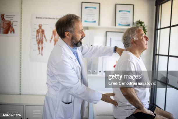 physical therapist examining senior patient's back injury at doctor's office - spinal column stock pictures, royalty-free photos & images