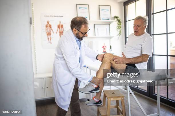 physiotherapeuten überprüfen das knie des patienten bei der arztpraxis - knie stock-fotos und bilder