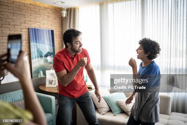 vater und sohn werden beim singen zu hause gefilmt - singing inside stock-fotos und bilder