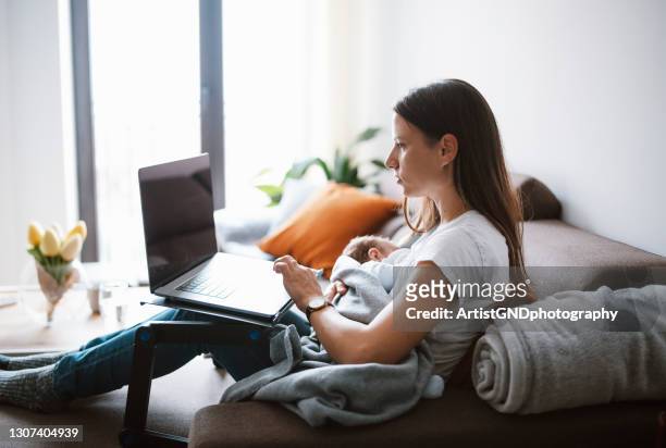 multi-tasking mother working on her laptop while breastfeeding her newborn baby at home. - leanincollection stock pictures, royalty-free photos & images