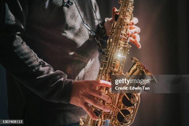lifehack asiatique chinois mature homme pratiquant le saxophone à la maison pendant le temps de loisirs week-end - saxophone photos et images de collection