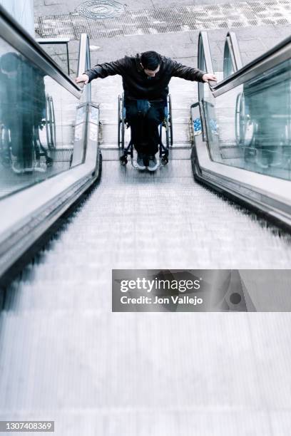 handicapped man starting up the escalator with his wheelchair. - southern european descent bildbanksfoton och bilder