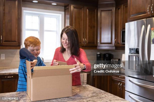 moeder en zoon die een packgage thuis ontvangen en openen - online shopping opening package stockfoto's en -beelden