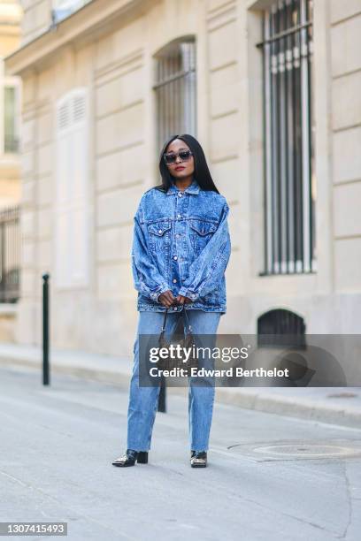 Carrole Sagba @linaose wears sunglasses, a blue denim jacket, blue jeans from Zara, a brown Fendi monogram printed bag, Balenciaga boots, on March...