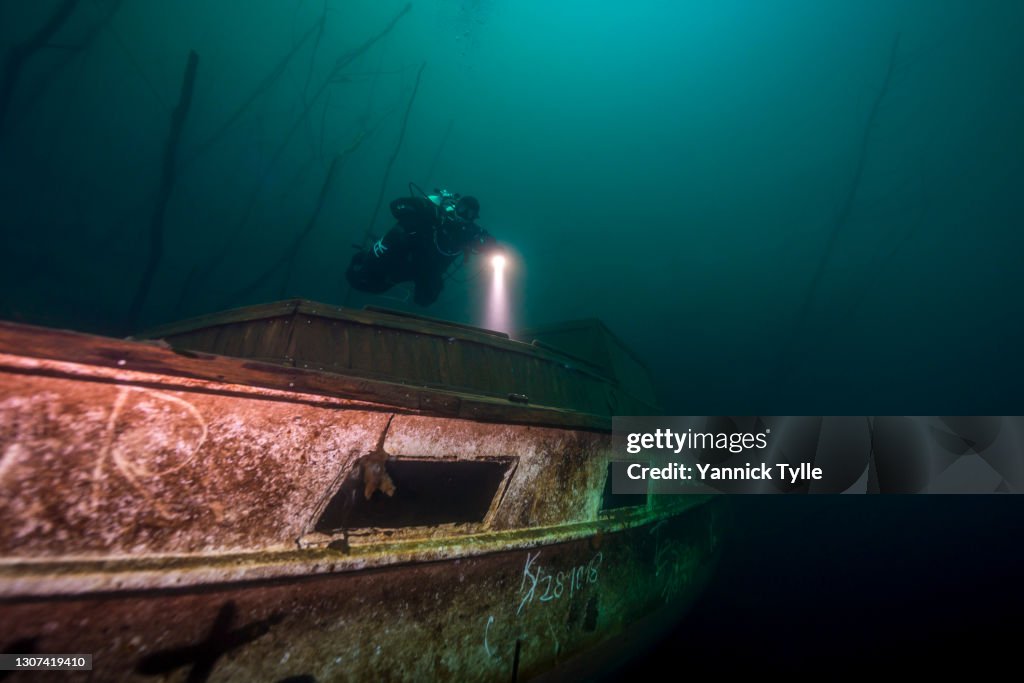 Scuba diver explores boat wreck in a quarry lake