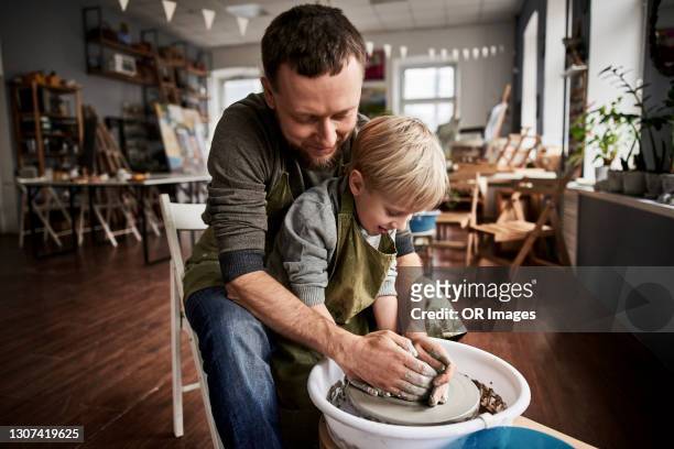 father and son doing pottery together in a workshop - pottery wheel stock pictures, royalty-free photos & images