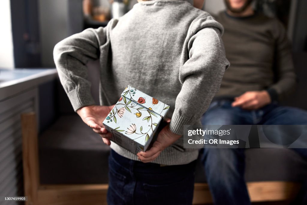 Boy hiding gift for his father behind the back