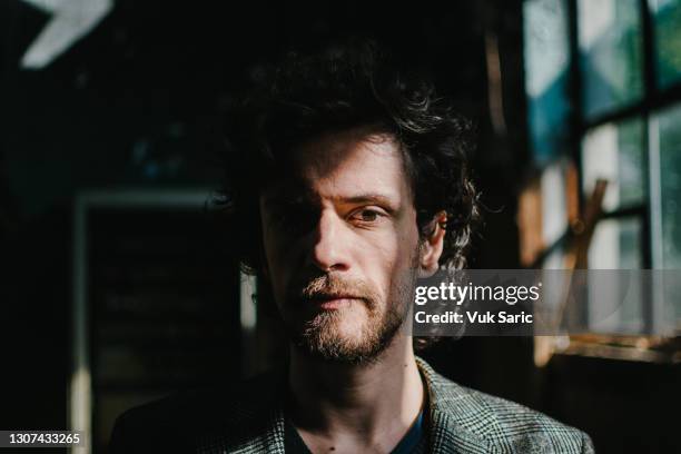 portrait of a bearded man standing in a dark room - alto contraste imagens e fotografias de stock