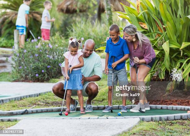 famiglia interrazziale, due bambini giocano a minigolf - minigolf foto e immagini stock