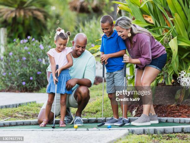 familia interracial, dos niños jugando al minigolf - miniature golf fotografías e imágenes de stock