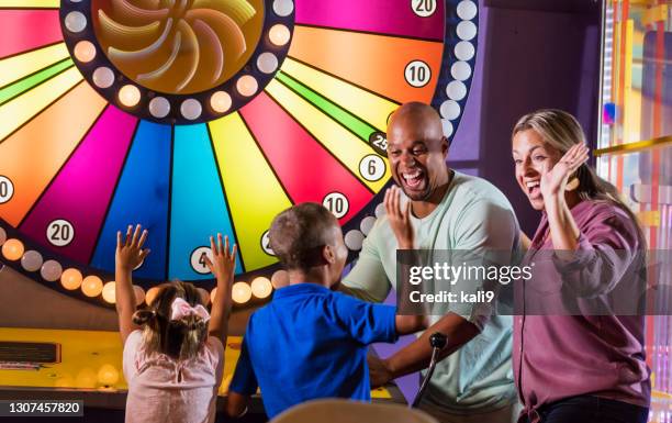 famille interraciale, deux enfants gagnant un jeu d’arcade - jeux darcade photos et images de collection