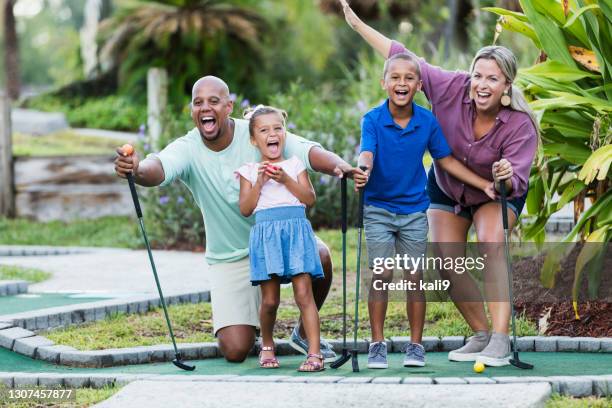 interracial family, two children playing miniature golf - miniature golf stock pictures, royalty-free photos & images