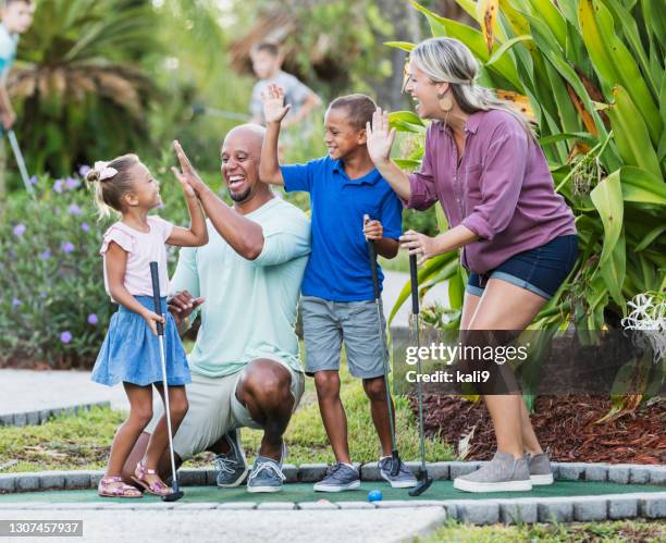 interracial family, two children playing miniature golf - putting clothes son stock pictures, royalty-free photos & images